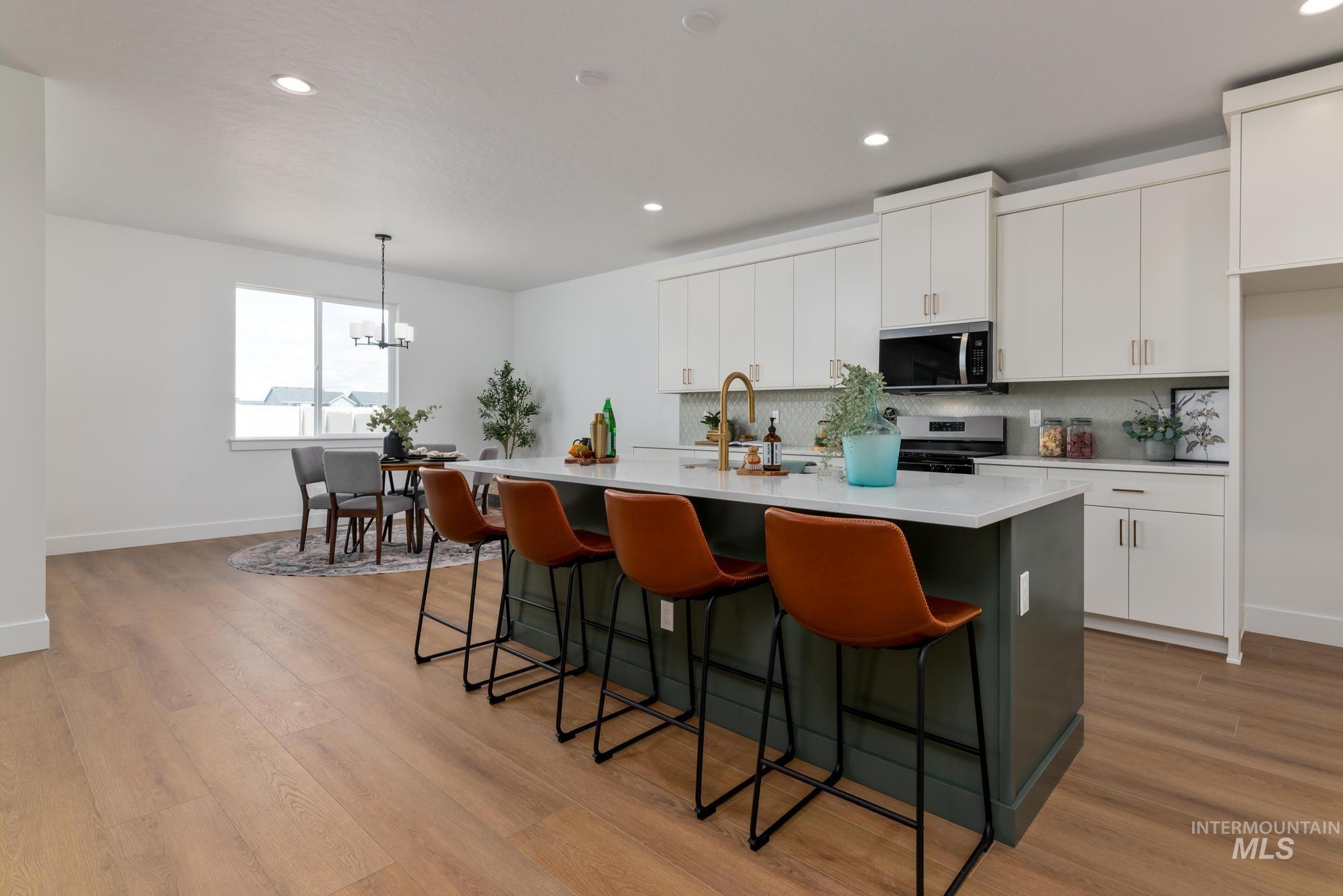 1925 Buckbrush Avenue Middleton, ID 83644 - Photo 5 of 20 Spacious kitchen featuring an island with countertop seating, white cabinetry, integrated stainless steel appliances, and wood-finish flooring