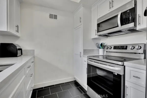 a bed sitting in a spacious bedroom next to a window and a potted plant