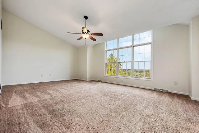 an empty room with windows and chandelier fan