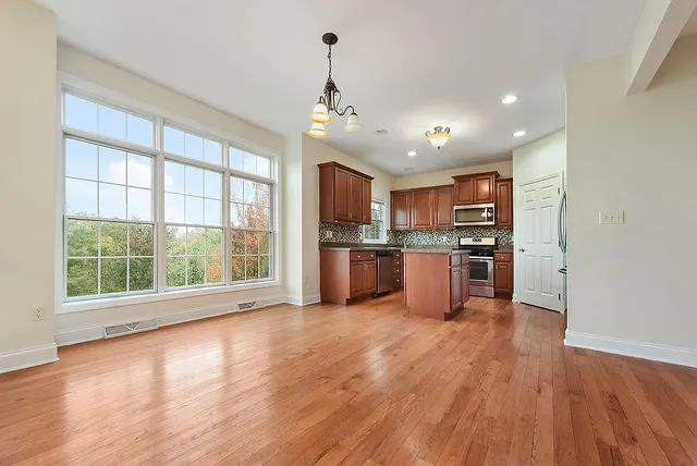 a open kitchen with stainless steel appliances granite countertop a stove top oven a refrigerator with island and wooden floor