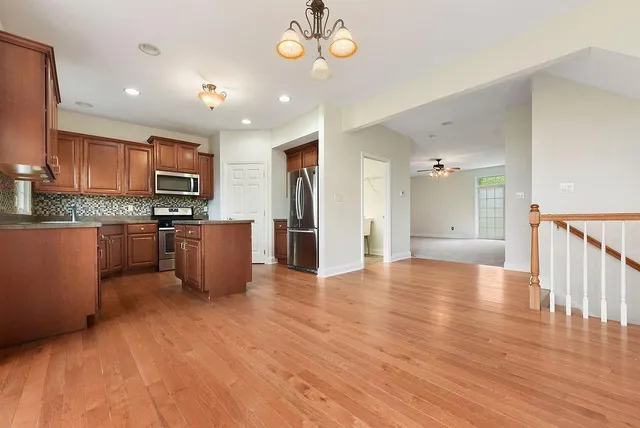 an open kitchen with wooden floor and stainless steel appliances