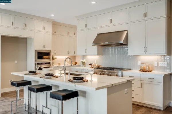a kitchen with stainless steel appliances a stove a sink and white cabinets