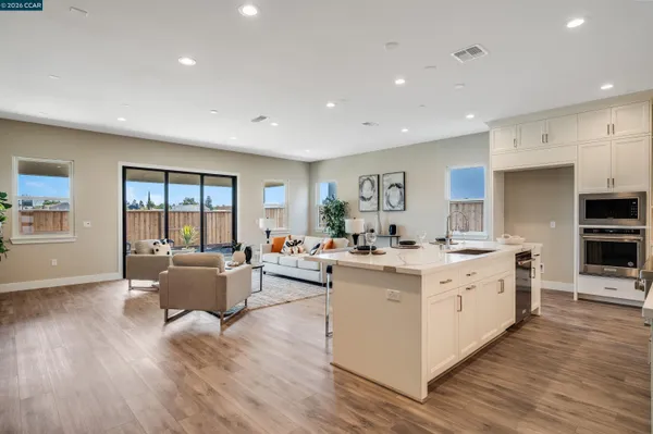 a large kitchen with stainless steel appliances a large counter top a couch and a view of living room