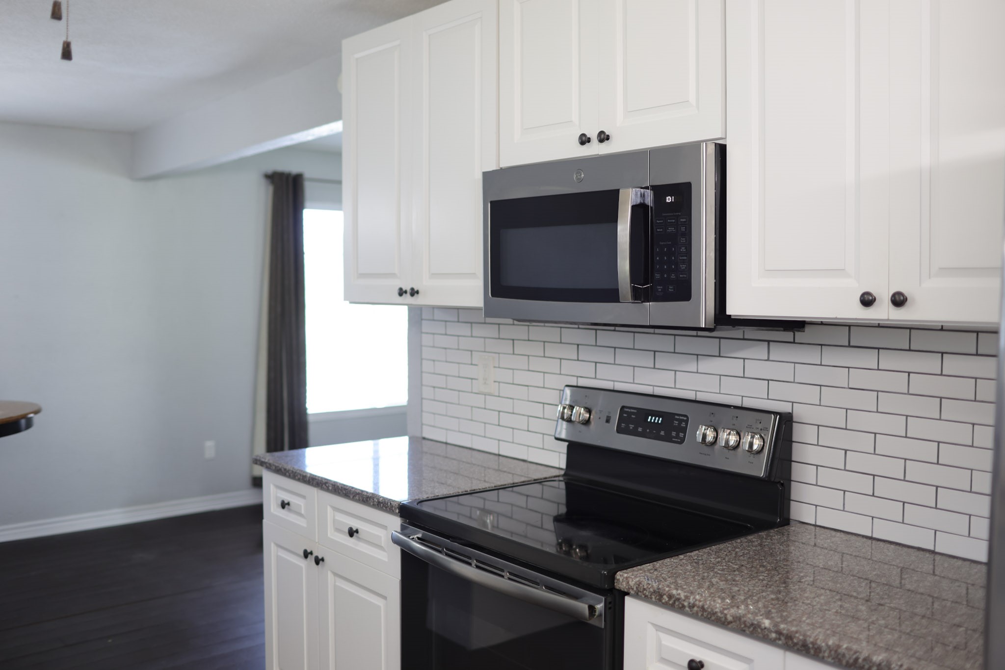 407 Tamarind Street Lake Jackson, TX 77566 - Photo 17 of 36 Modern kitchen with sleek white cabinets, granite countertops, and stainless steel appliances. The subway tile backsplash adds a contemporary touch. Bright and airy atmosphere.