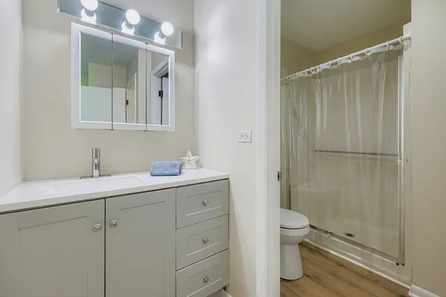 a bathroom with a granite countertop sink toilet a mirror and shower