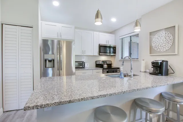 a kitchen with granite countertop a refrigerator a stove a sink a dining table and chairs