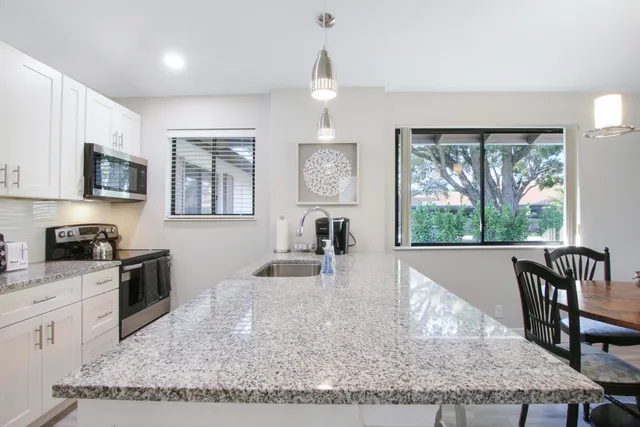 a kitchen with granite countertop a stove a sink a dining table and chairs