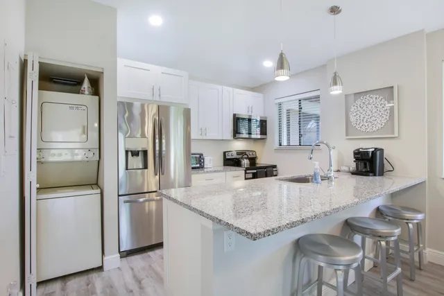 a kitchen with granite countertop kitchen island stainless steel appliances a refrigerator a stove a sink a dining table and chairs