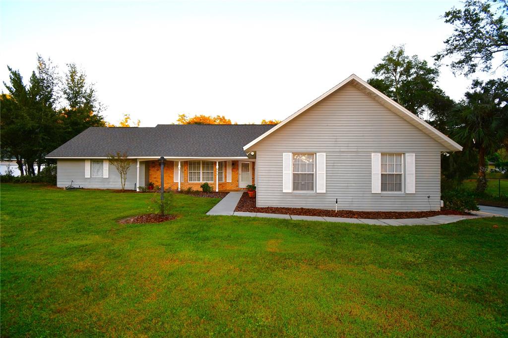 a view of a yard in front of a house with plants and large tree