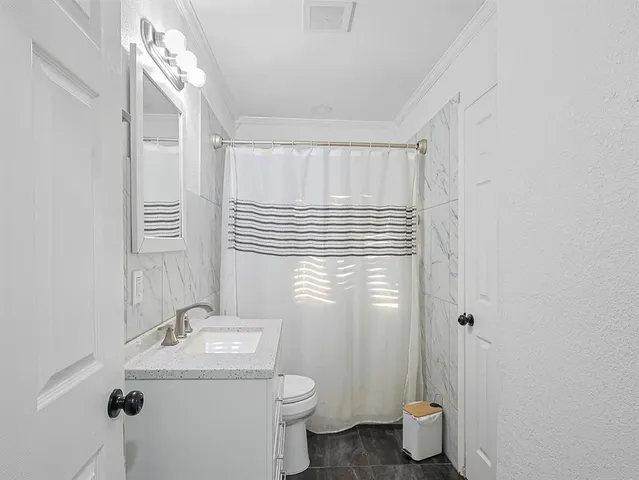 a bathroom with a granite countertop sink toilet and a mirror