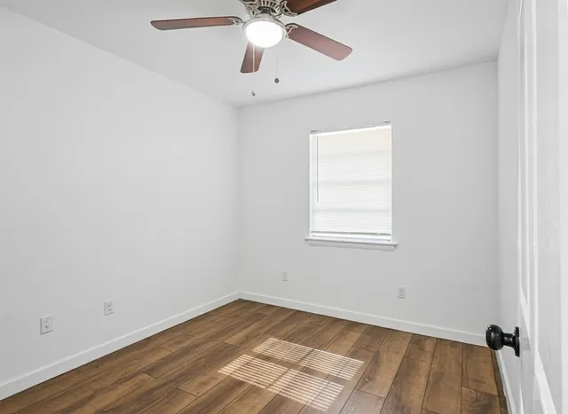 an empty room with a window and a ceiling fan