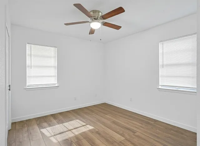 an empty room with a window and a ceiling fan