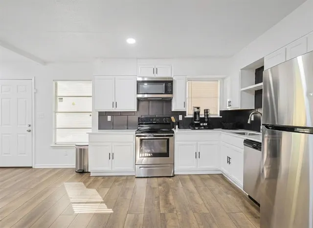 a kitchen with a refrigerator stove and white cabinets
