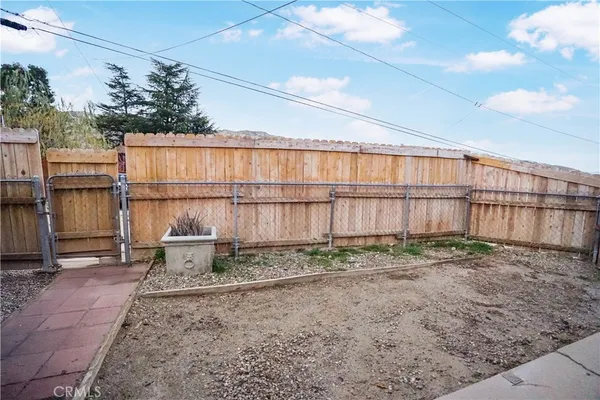a backyard of a house with large trees and wooden fence