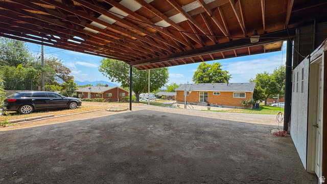 120 North 1230 E Street Springville, UT 84663 - Photo 43 of 60 Covered outdoor parking area featuring exposed wood beam ceiling, gravel ground cover, and a detached storage shed