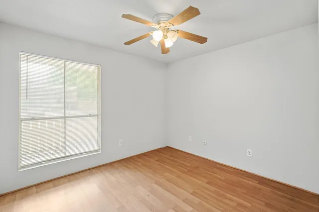 an empty room with a window and a fan
