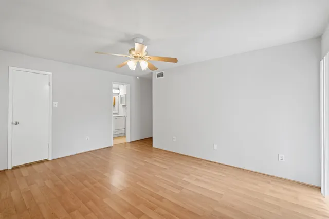 a view of an empty room with chandelier fan and wooden floor
