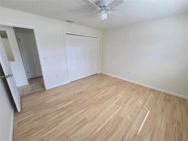 an empty room with wooden floor and fan
