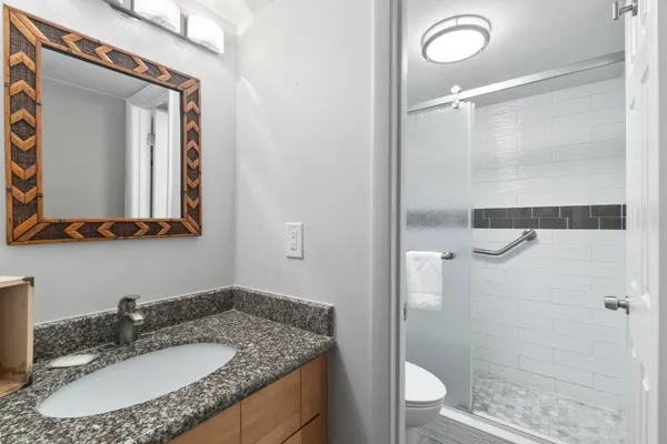 a bathroom with a granite countertop sink toilet and shower