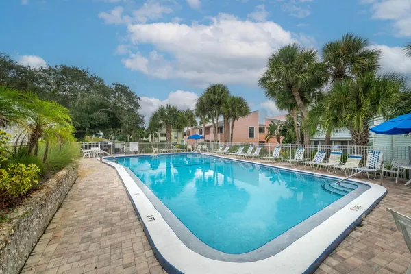 a view of swimming pool that has lawn chairs with plants and trees