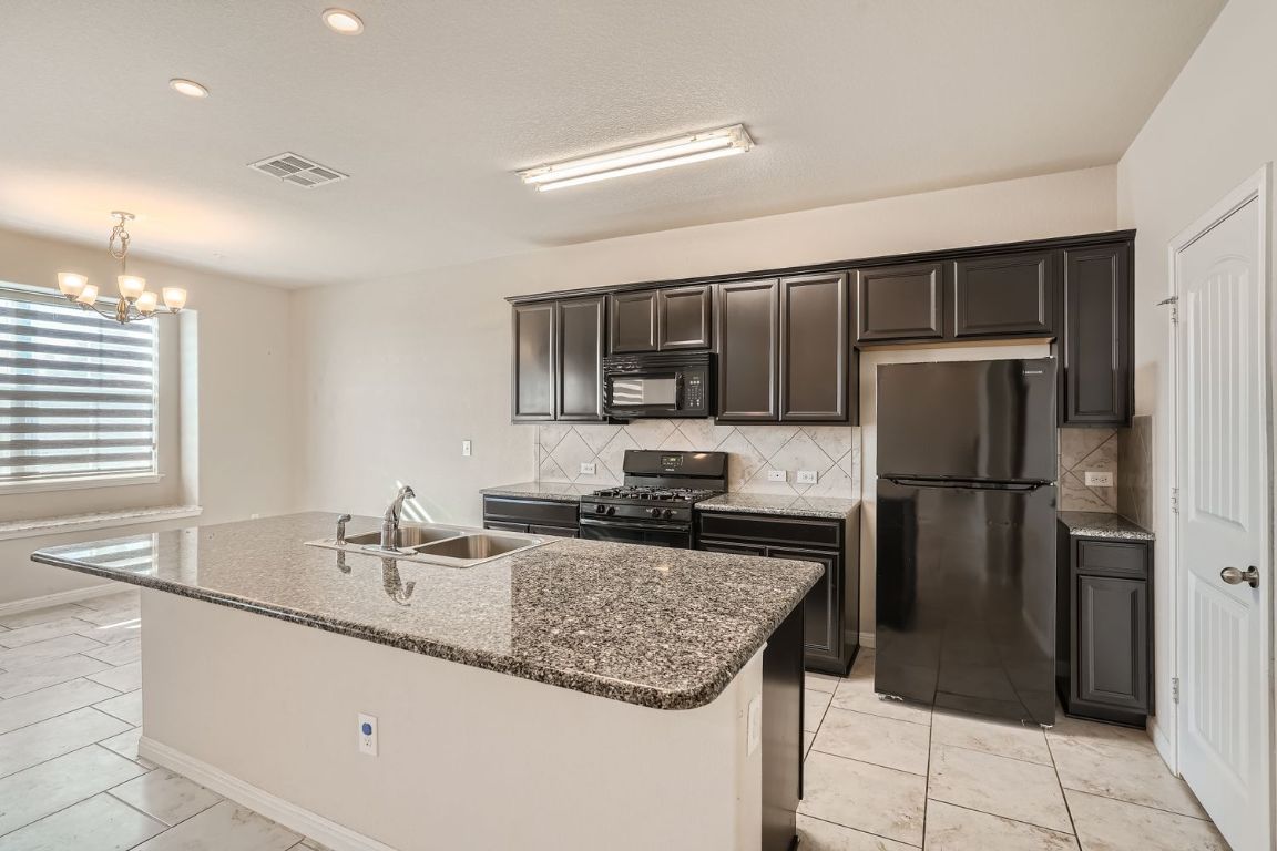 403 Epiphany Lane Pflugerville, TX 78660 - Photo 10 of 29 a kitchen with kitchen island granite countertop a sink stove and refrigerator