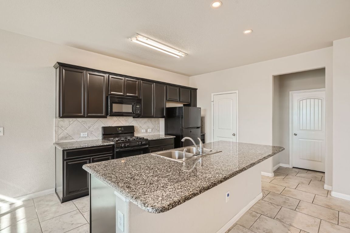 403 Epiphany Lane Pflugerville, TX 78660 - Photo 12 of 29 a kitchen with stainless steel appliances granite countertop a sink stove and refrigerator