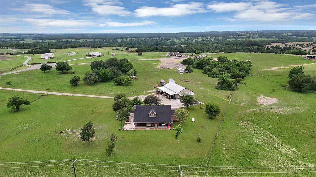 100 Shadle Ridge Court Poolville, TX 76487 - Photo 37 of 40 Expansive green acreage featuring a single-story residence with a dark shingle roof and a covered porch