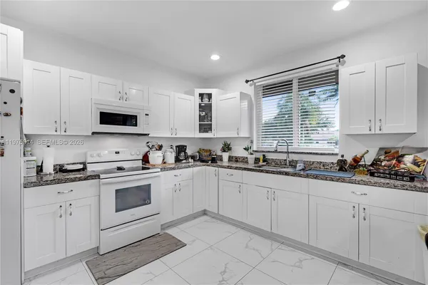 a kitchen with white cabinets sink and appliances