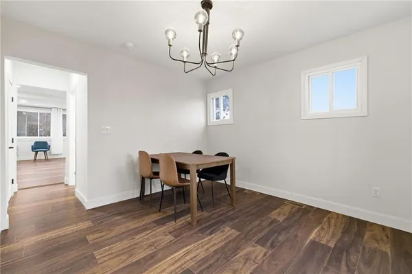 a view of a dining room with wooden floor a chandelier a wooden table and chairs