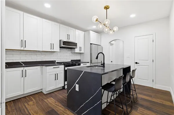 a kitchen with stainless steel appliances a white table chairs and a refrigerator