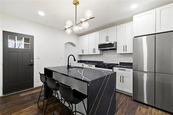 a kitchen with stainless steel appliances granite countertop a sink a stove a refrigerator and island with wooden floor
