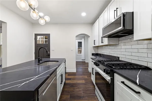 a kitchen with kitchen island stainless steel appliances a sink cabinets and wooden floor