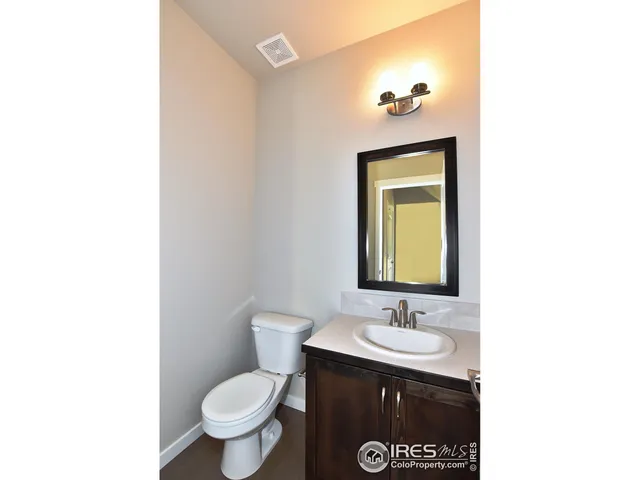a bathroom with a granite countertop sink toilet and mirror
