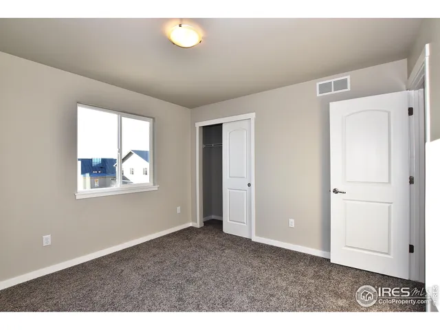 a view of an empty room with window and closet area