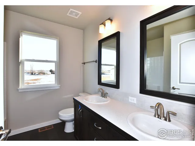 a bathroom with a toilet a sink a mirror and a window