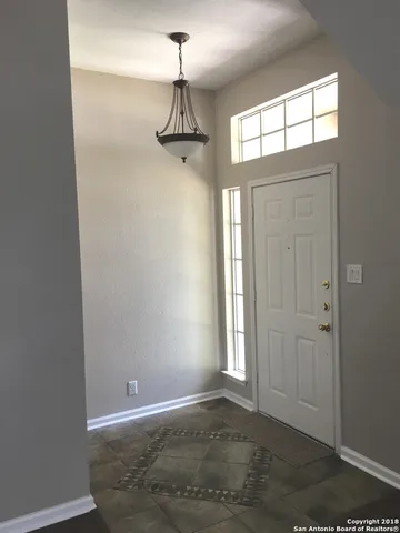 an empty room with windows and chandelier fan