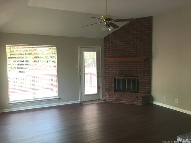 a view of a livingroom with a fireplace window and wooden floor
