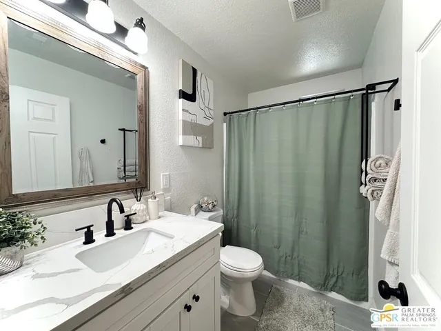 a bathroom with a sink a toilet a mirror and shower curtain