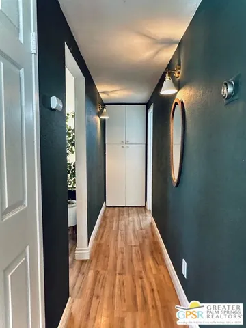a view of a hallway with wooden floor and a mirror