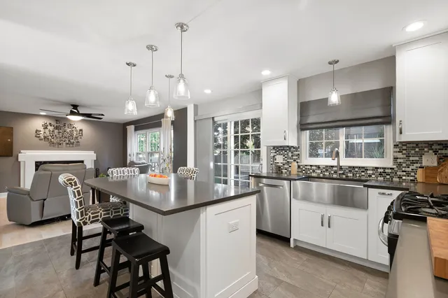 a kitchen with stainless steel appliances kitchen island granite countertop a dining table chairs and white cabinets