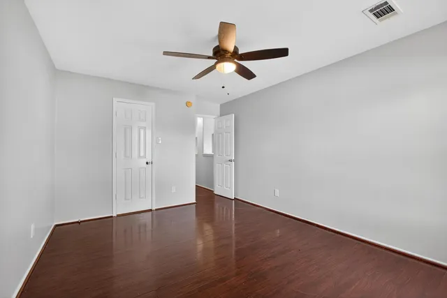 a view of empty room with wooden floor and fan
