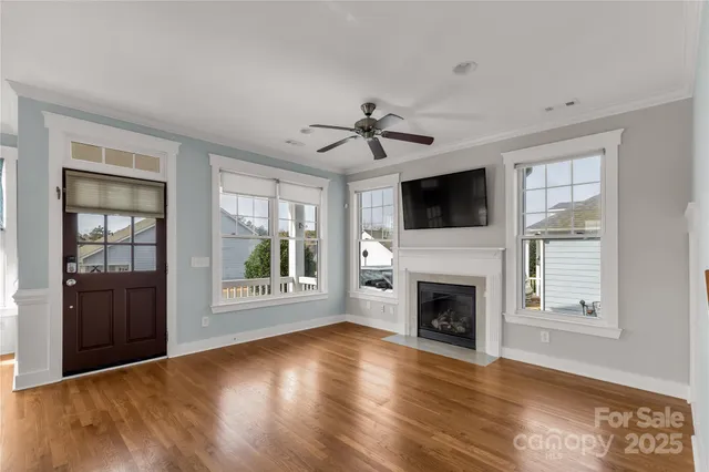 a view of an empty room with wooden floor fireplace and a window