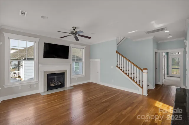 a view of an empty room with wooden floor fireplace and a window