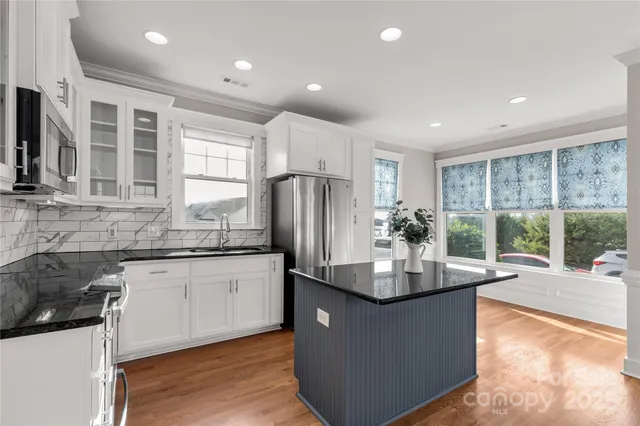 a kitchen with kitchen island granite countertop a sink and refrigerator