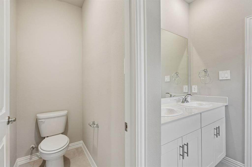 1712 Arches Road Anna, TX 75409 - Photo 23 of 37 a bathroom with a toilet sink vanity and mirror