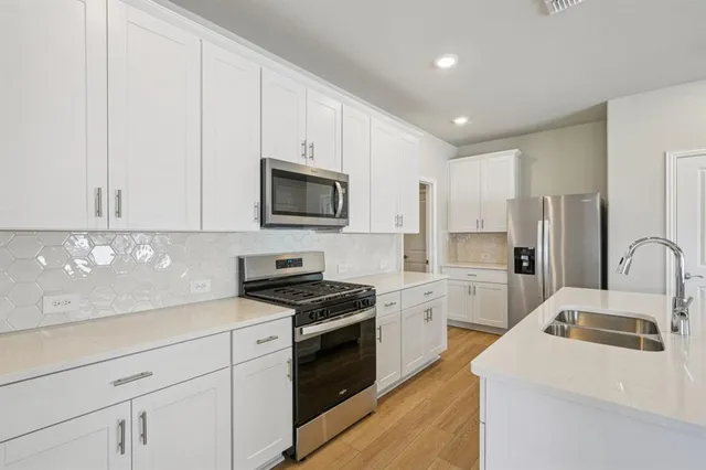 a kitchen with granite countertop white cabinets stainless steel appliances and sink