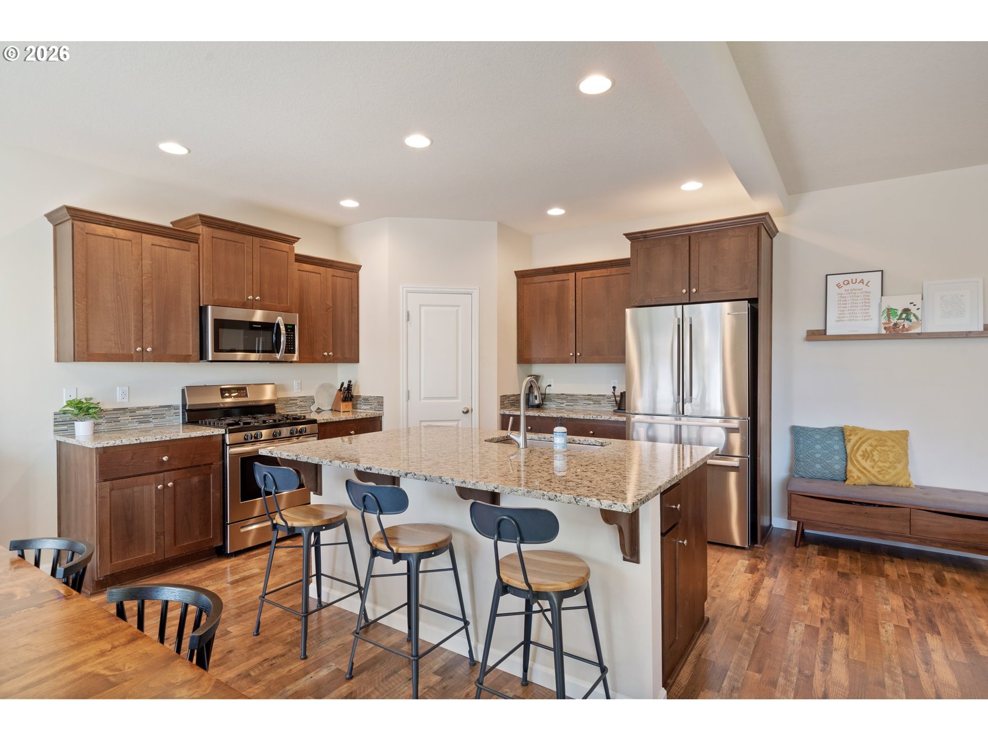 16185 Northwest Liberty Street Portland, OR 97229 - Photo 8 of 33 a kitchen with stainless steel appliances kitchen island granite countertop a refrigerator a stove a sink a dining table and chairs with wooden floor