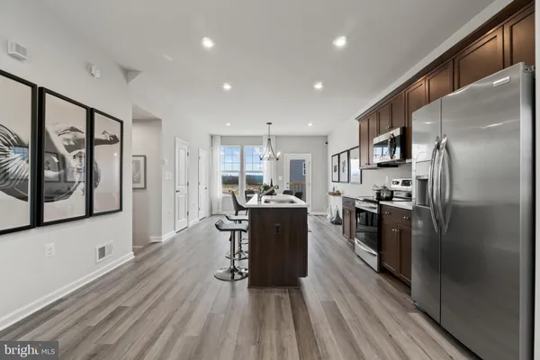a kitchen with a sink a stove a refrigerator cabinets and a dining table with wooden floor