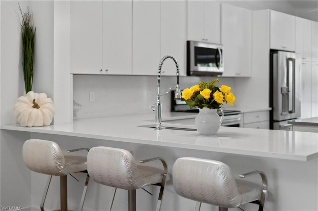 1970 Willow Bend Circle, Unit 203 Naples, FL 34109 - Photo 3 of 42 a kitchen with stainless steel appliances granite countertop a table and a microwave