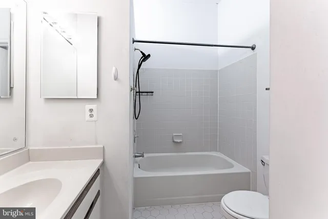 a bathroom with a tub shower vanity and toilet